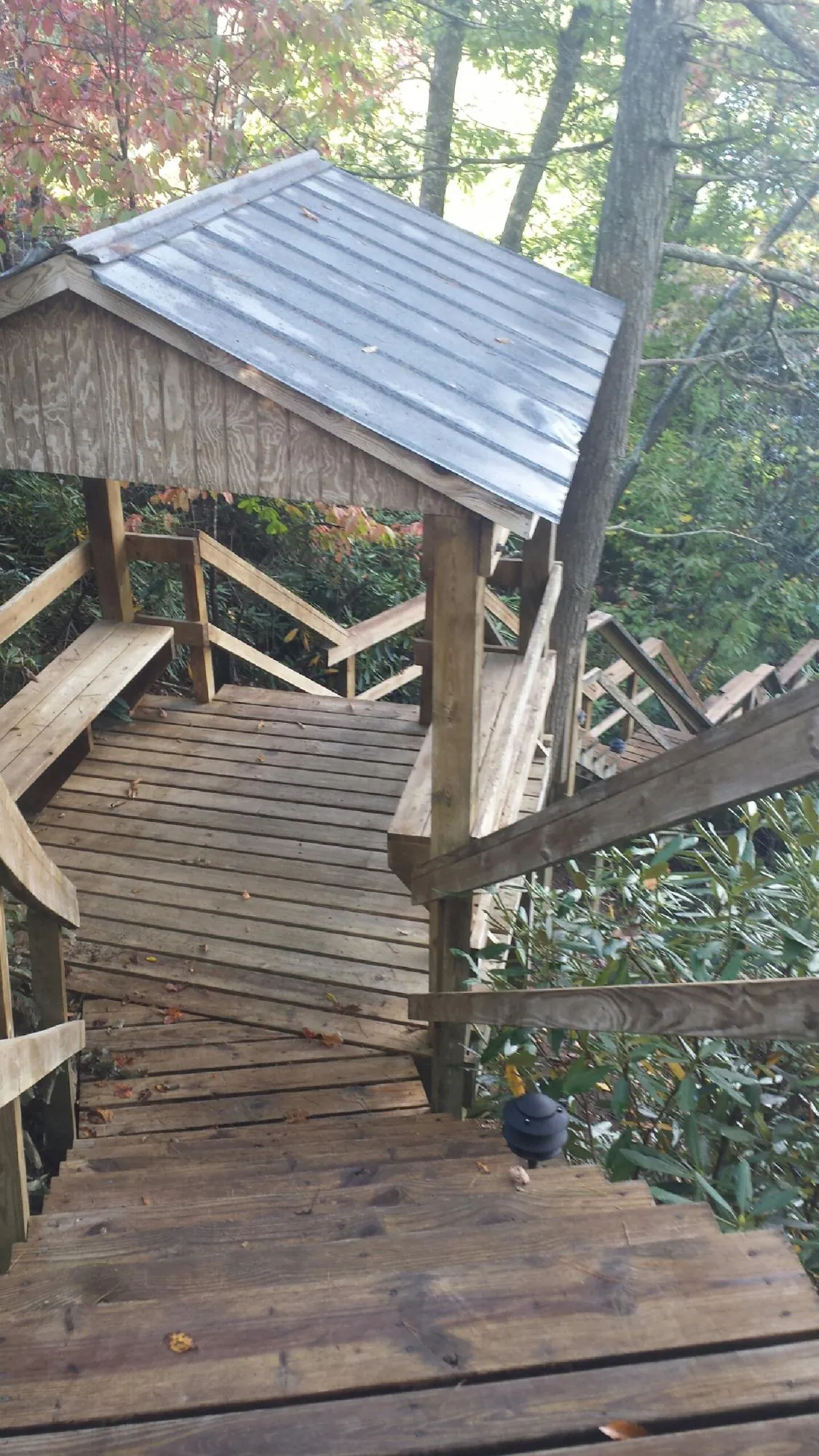 Metal roofed shelter over wooden steps on a wooded walkway — Skylight Repair & Installation work by our crew in Grantsville