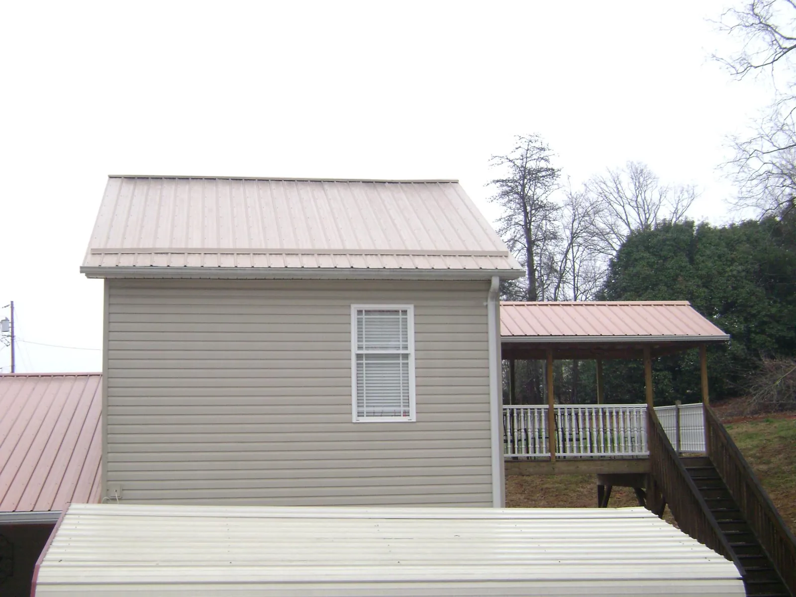 Tan metal roofs on a two story addition and attached porch, from a Roof Replacement job in Grantsville